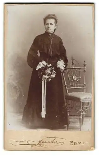 Fotografie J. Fuchs, Berlin, Friedrichstr. 108, Junge Dame im weiten schwarzen Kleid mit einem Bouquet Blumen