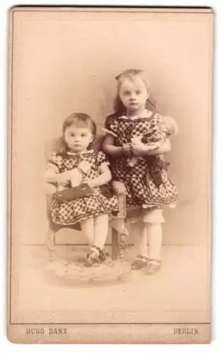 Fotografie Hugo Danz, Berlin, Jerusalemer Str. 28, Zwei kleine Mädchen in karierten Kleidern mit ihren Puppen