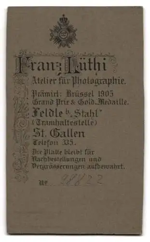 Fotografie Franz Lüthi, Feldle-St. Gallen, Kleinkind im weissen Gewand mit grossen Augen auf einem Pelz