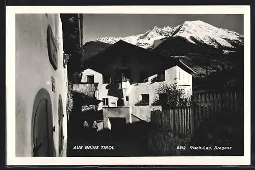 AK Grins /Tirol, Ortspartie gegen schneebedeckten Berg