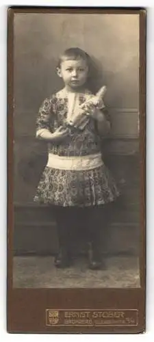 Fotografie Ernst Stober, Bromberg, Elisabethstrasse 12 /14, Kind im gemusterten Kleidchen, mit Ponyfrisur und Puppe