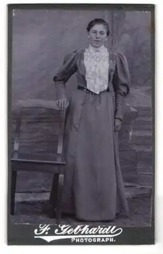 Fotografie Ferd. Gebhardt, Treuchtlingen, Bahnhofstrasse, Junge Dame im Puffärmelkleid mit Zierlatz vor Fotokulisse