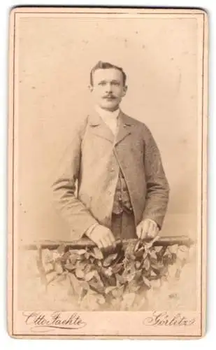 Fotografie Otto Faehte, Görlitz, Grüner Graben 29, Junger eleganter Herr im hellen Anzug an einem bewachsenen Geländer