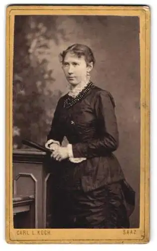 Fotografie Carl L. Koch, Saaz, Ringplatz 42, Junge Frau im taillierten Kleid mit Rüschenkragen, mit markanter Kette
