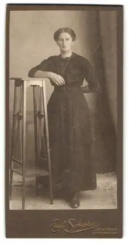 Fotografie Emil Schröter, Jüterbog-Luckenwalde, Trebbinerstr. 6, Junge Frau im taillierten Kleid an einem hohen Tisch