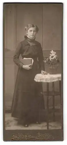 Fotografie Ad. Winkler, Görlitz, Berliner-Str. 12, Junge Frau im Kleid mit markantem Stehkragen, ein Buch in der Hand
