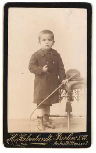 Fotografie H. Haberlandt, Berlin, Anhalt-Strasse 2, Kleiner Junge im Mantel mit einer Reitgerte