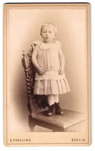 Fotografie E. Faehling, Berlin, Leipziger-Strasse 63a, Junges Mädchen im kurzärmeligen Kleid auf einem Stuhl stehend