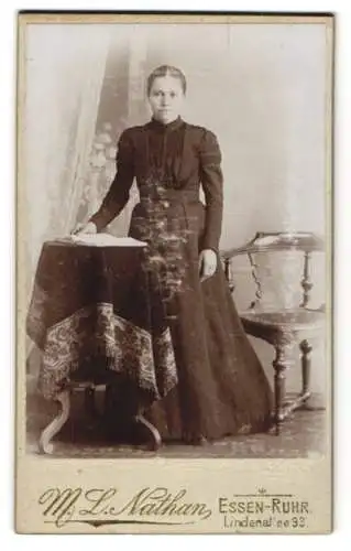 Fotografie M. L. Nathan, Essen-Ruhr, Lindenallee 93, Junge Dame mit tailliertem Kleid an einem Beistelltisch