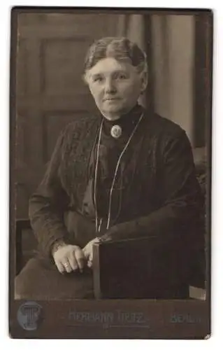 Fotografie Hermann Tietz, Berlin, Leipziger-Str., Alte bürgerliche Dame im schwarzen Kleid mit markanter Brosche