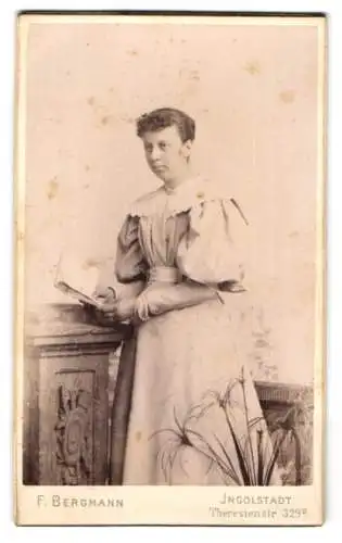 Fotografie F. Bergmann, Ingolstadt, Theresienstr. 329, Junge Dame im hellen Kleid mit weiten Puffärmeln und einem Buch
