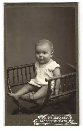 Fotografie M. Hirschbeck, Landsberg a. Lech, Kleinkind im weissen Gewand mit leichtem Lächeln