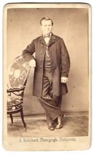 Fotografie A. Reinhard, Pirmasens, Jugendlicher Knabe im Anzug mit einem Mantel und einer Fliege