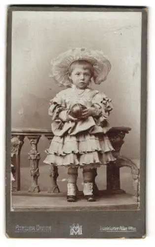 Fotografie Atelier Osten, Berlin, Kleines Mädchen im mehrlagigen Kleid mit grossem Hut und einem Spielball