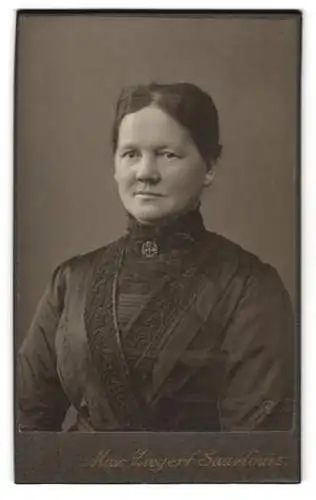 Fotografie Max Ziegert, Saarlouis, Bürgerliche Frau im schwarzen Kleid mit verziertem Revers und Brosche am Kragen