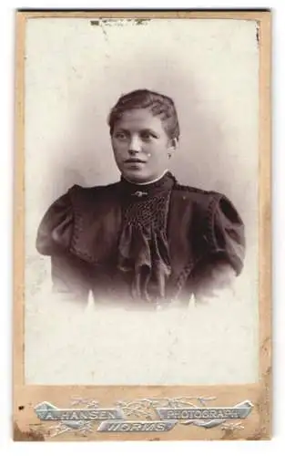 Fotografie A. Hansen, Worms, Hagenstrasse 26, Junge Dame im schwarzen Kleid mit breiter Schulterpartie und Anstecknadel
