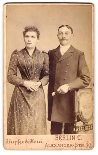 Fotografie Kupfer & Heim, Berlin, Alexander-Str. 30, Bürgerliches Ehepaar, sie im stark taillierten Kleid, er im Mantel