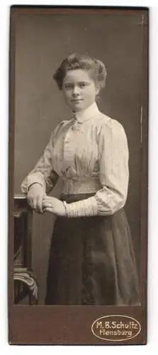 Fotografie M. B. Schultz, Flensburg, Junge Dame mit zurückgestecktem Haar in gestreifter Bluse und dunklem Rock