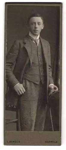 Fotografie L. Hansen, Kappeln, Jugendlicher Knabe im Dreiteiler mit Krawatte und Matrosenmütze in der Hand