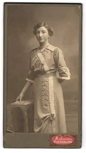 Fotografie A. Juul, Flensburg, Junge Frau im taillierten Kleid mit Rüschen-Elementen an den Ärmeln und der Front