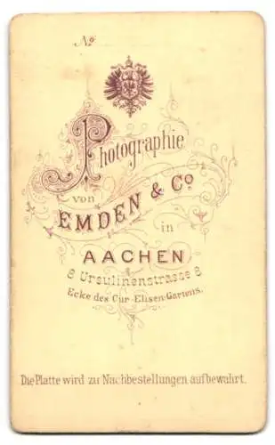Fotografie Emden & Co., Aachen, Ursulinenstrasse 8, Junger Mann mit lockigem Haar im Mantel mit breitem Revers