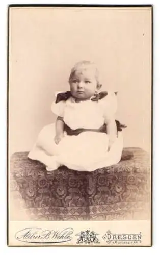 Fotografie Atelier B. Wehle, Dresden, Marienstr. 44, Kleinkind im weissen Kleid mit schwarzen Schleifen an den Schultern