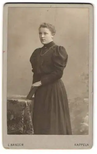 Fotografie L. Hansen, Kappeln, Junge Frau im schwarzen taillierten Kleid mit Puffärmeln, mit einem Buch in der Hand