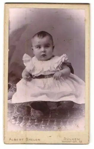 Fotografie Albert Breuer, Dulken, Venloer-Str. 58, Niedliches Baby im weissen Rüschenkleid mit Gürtel und glattem Haar