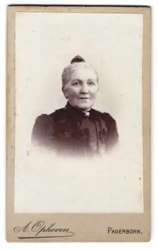 Fotografie A. Ophoven, Paderborn, Ältere schöne Dame im schwarzen Kleid mit silberner Brosche und leichtem Lächeln