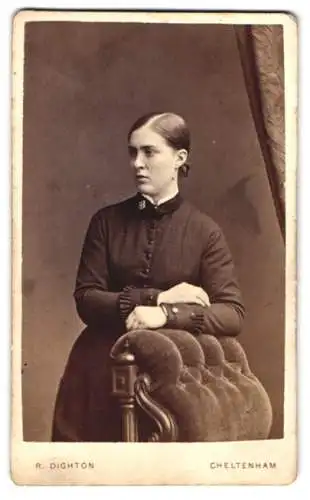 Fotografie R. Dighton, Cheltenham, Junge Dame im dunklen Kleid mit heller Brosche und Zopf im Mittelscheitel