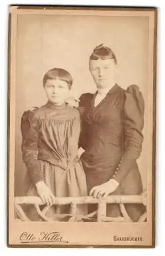 Fotografie Otto Hiller, Saarbrücken, Zwei junge Schwestern in dunklen Kleidern mit kurzen Ponies und Hochsteckfrisuren