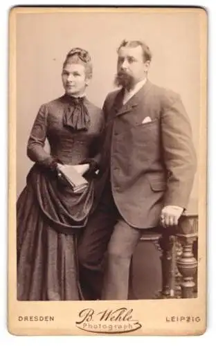 Fotografie B. Wehle, Dresden, Marienstr. 10, Elegantes junges Paar in schwarzer Kleidung mit Vollbart und Buch
