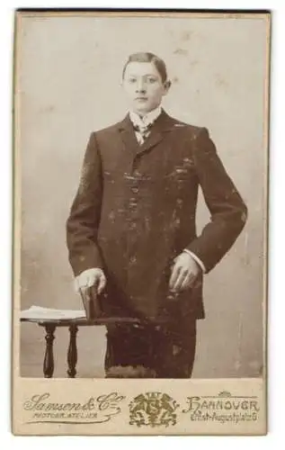 Fotografie Samson & Co., Hannover, Ernst-Augustplatz 5, Junger adretter Mann im schwarzen Anzug mit Fliege und Buch