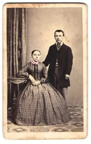 Fotografie B. Sparmeyer, Herrnhut, junges Paar im karierten Reifrockkleid und im dunklen Anzug