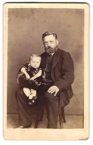 Fotografie Louis Füllgraf, Züllichau, Vater im Anzug mit seiner kleinen Tochter auf dem Schoss