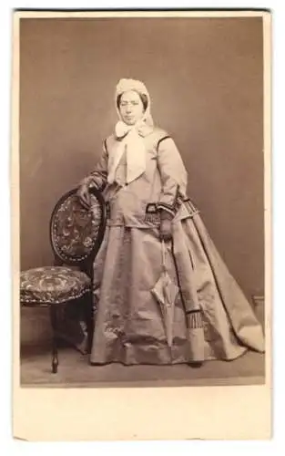 Fotografie Julius Roske, Ort unbekannt, junge Frau im Winterkleid mit Haube und Schirm in der Hand