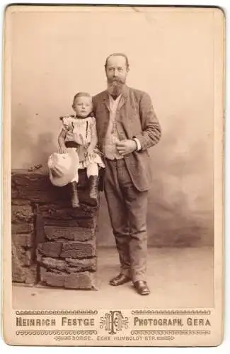 Fotografie Heinrich Festge, Gera, älterer Herr im Anzug mit seiner Enkeltochter auf der Mauer