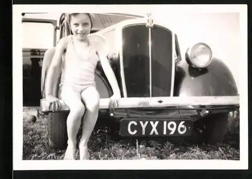 Fotografie Auto, niedliches Mädchen auf Stossstange sitzend