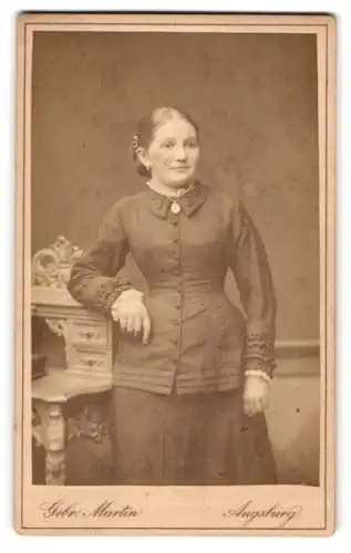 Fotografie Gebrüder Martin, Augsburg, Bahnhofstrasse, Junge dame im taillierten Kleid an einem Sekretär