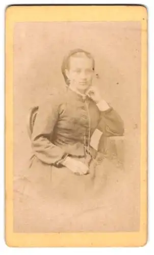 Fotografie M. Keller, Augsburg, Junge Dame im tallierten Kleid an einem Tisch sitzend, den Kopf auf die Hand gestützt