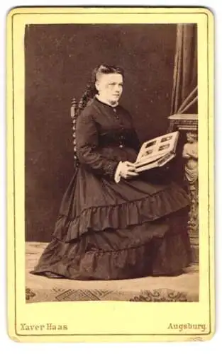 Fotografie Xaver Haas, Augsburg, Jesuitengasse 414, Bürgerliche Frau im weiten Kleid mit einem Fotoalbum