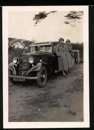 Fotografie Auto, Damen lehnen an Limousine mit Kühlerabdeckung