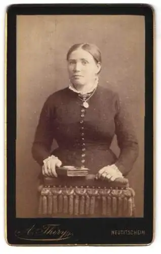 Fotografie A. Thiry, Neutitschein, Junge Dame im taillierten Kleid mit fragendem Blick und einem Buch