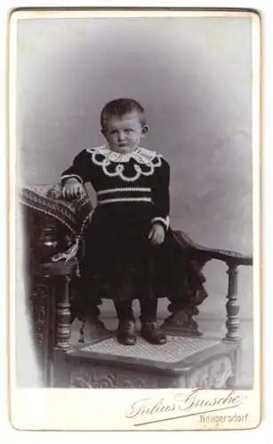 Fotografie Julius Grusche, Neugersdorf i. S., Kleines Mädchen im schwarzen, verzierten Kleid mit enttäuschtem Blick