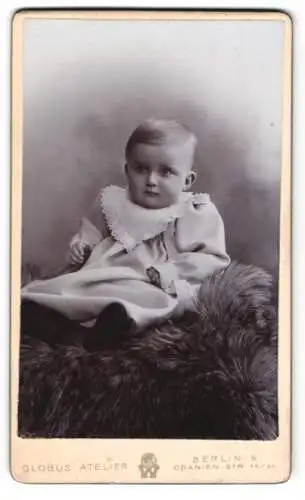 Fotografie Globus Atelier, Berlin, Oranien-Str. 52 /53, Kleines Kind im weissen Gewand mit Rüschenkragen auf einem Pelz