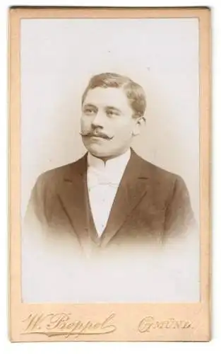 Fotografie W. Boppel, Gmünd, Junger Mann mit Seitenscheitel und gezwirbeltem Schnurrbart im Anzug mit weisser Fliege