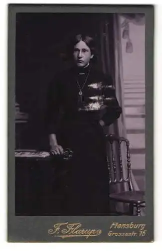 Fotografie F. Flarup, Flensburg, Grossestr. 75, Junge Frau im Kleid mit Taillengürtel mit grosser Schleife im Haar