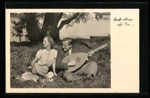 AK Junges Paar sitzt unterm Baum, er spielt Gitarre, sie hat Blumen gepflückt