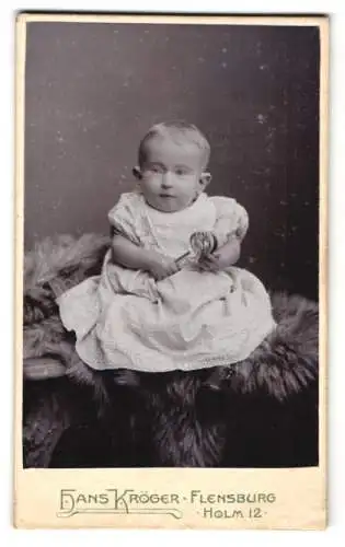 Fotografie Hans Kröger, Flensburg, Holm 12, Niedliches Kleinkind im Kleid mit Rassel