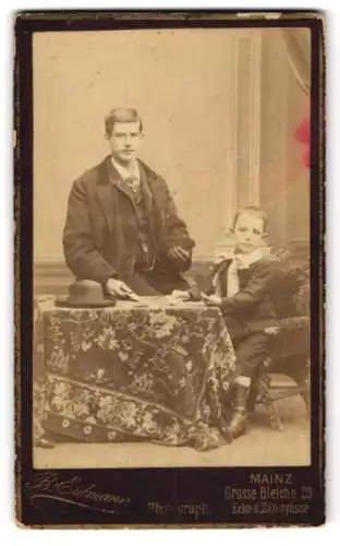 Fotografie B. Erdmann, Mainz, Grosse Bleiche 23, Ein junger Mann mit seinem Sohn am Tisch, beide in Sonntagsgarderobe